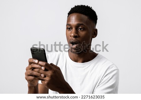 Portrait close up shot of african american black guy holding new modern laste series cellphone smartphone in hands observing photos receiving bad news emotional guy stunned terrified.