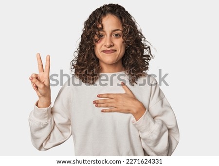 Radiant young woman with stunning curls taking an oath, putting hand on chest.