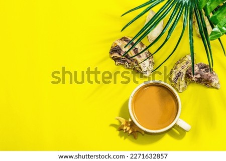 A cup of coffee in a marine style. Starfish, oysters, palm leaves. Hard light, dark shadow, bright yellow background, flat lay, top view