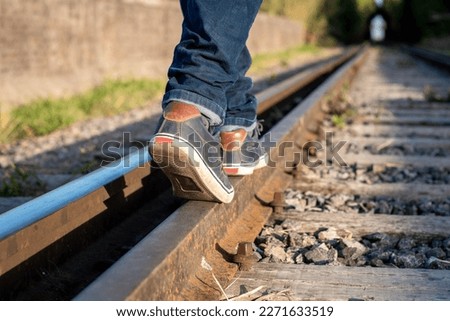 Person walking on the train tracks. Feet of person on the train tracks. Person walking following the train tracks. Mode of transportation. concept photo