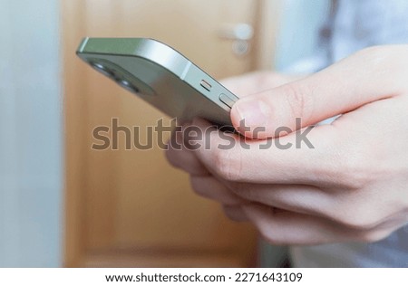 Side view. Hand of man or woman using smartphone in the living room at home, typing message, texting or scrolling the news, shopping. Close-up of hands. High quality horizontal photo