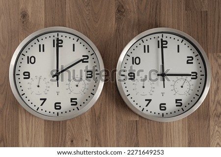 Two clocks, one showing two o'clock, the other showing three o'clock.  Time change symbol.  Shift to daylight saving time. Transition of time. Moving the hands forward. Royalty-Free Stock Photo #2271649253