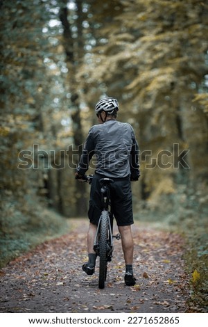 man riding his mountain bike in the forest in summer, man standing with his bike in the forest, mountain biking