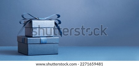 Two Luxury gift boxes with a blue bow on dark blue. Side view monochrome . Fathers day or Valentines day gift for him. Corporate gift concept or birthday party. Festive sale copy space banner