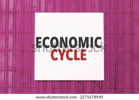 white sticker with text economic cycle on pink wooden background