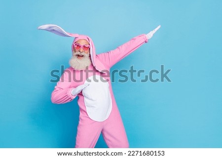 Photo of cheerful good mood man dressed pink rabbit costume sunglass palms directing empty space isolated on blue color background