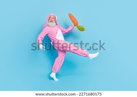 Full size profile photo of positive aged person walk arm hold carrot toy isolated on blue color background