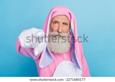 Photo of angry serious pensioner guy dressed bunny kigurumi pointing finger you isolated blue color background
