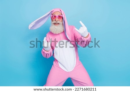 Photo of excited cool retired guy wear pink hare sleepwear heart glasses showing hard rock signs isolated blue color background
