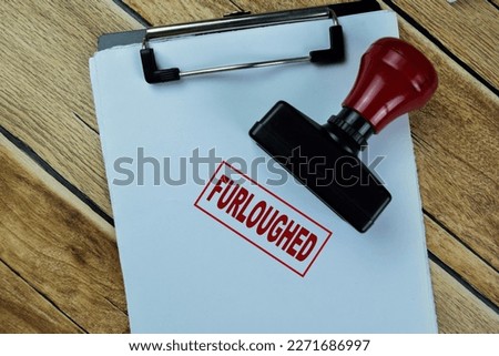 Concept of Red Handle Rubber Stamper and Furloughed text isolated on on Wooden Table.