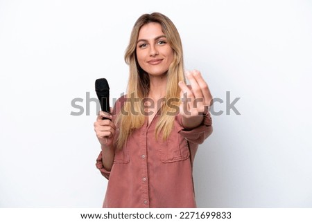 Singer Uruguayan woman picking up a microphone isolated on white background making money gesture