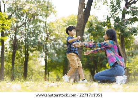 Asian little cute boy running to hug his mother at the park, mother and sun relaxation activity in a park or garden in weekend. Woman and a boy playing on a beautiful sunlight and bokeh background. Royalty-Free Stock Photo #2271701351