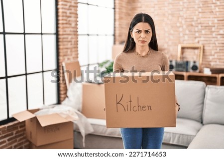 Young woman moving to a new home holding box skeptic and nervous, frowning upset because of problem. negative person. 