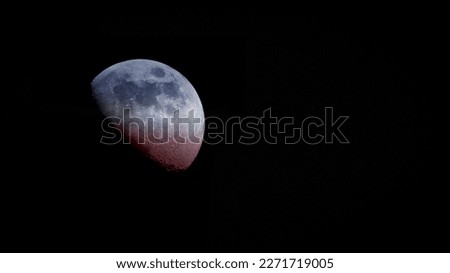 Close-up color photo of the moon shaded with red, white and blue colors against a black background. Copy space.