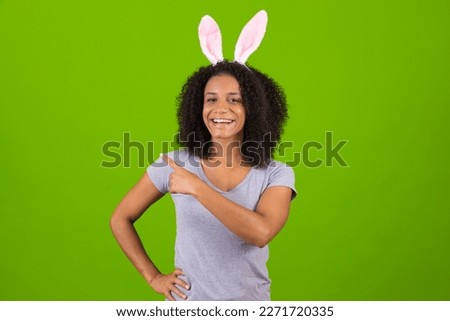 Closeup portrait of beautiful charming cheerful hair girl wearing pink bunny ears headband festive spring look isolated over green color background pointing on free space for text