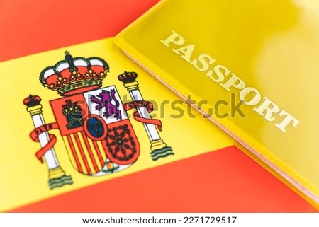 Flag of spain with passport. Travel visa and citizenship concept. residence permit in the country. a yellow document with the inscription passport is on the flag. Close up, top view Royalty-Free Stock Photo #2271729517