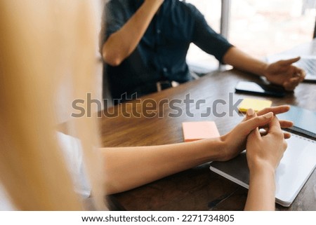 Close-up cropped shot of unrecognizable female and male businesspeople discussing deal, signing contract sitting at table. Negotiation appointment in boardroom. Take part in talk concept