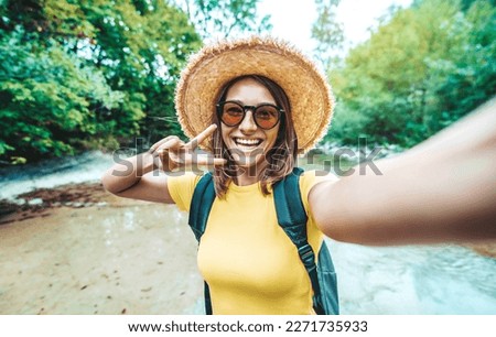Happy female tourist with backpack taking selfie picture with smart mobile phone outside - Millenial woman having fun on adventure trip - Traveling and technology concept