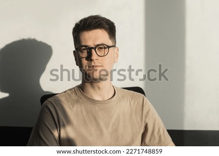 Headshot portrait smart businessman in glasses sitting at work desk in modern office, looking at camera, confident satisfied student freelancer posing for photo at workplace