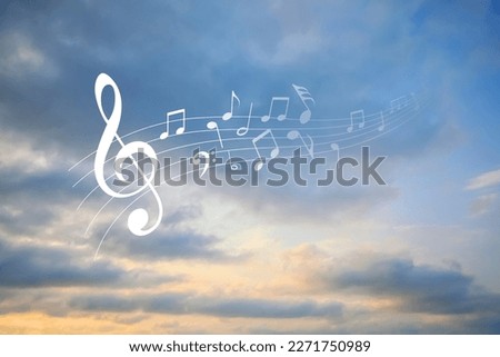 Staff with treble clef and musical notes against sunset sky