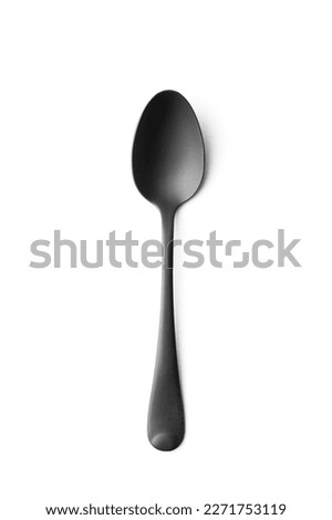 Metallic black matte spoon on white insulation, black cutlery on a white background top view.