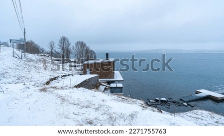 Holiday house on the shore of Fjord in Norway. winer scenery with snow, sea and cloudy sky. interesting wooden house by the sea. holiday in troms, northern Norway 