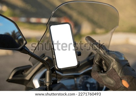 Close-up of a biker's hand pointing at the blank screen with mockup of his smartphone mounted on the scooter. Royalty-Free Stock Photo #2271760493