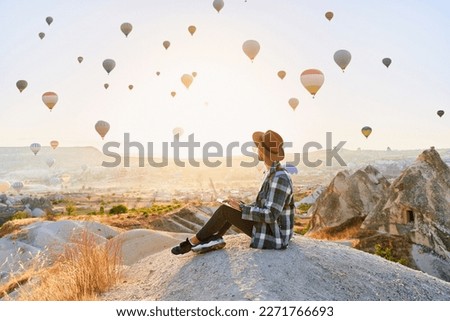 Freelancer working online at beautiful destination in Nevsehir, Goreme. Free inspired traveling blogger sitting alone on hill in scenic valley in Anatolia, Kapadokya Royalty-Free Stock Photo #2271766693