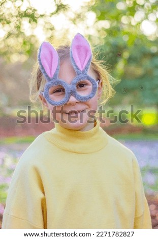smiling little girl in a glasses with rabbit ears in the park. Easter bunny funny costume