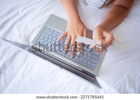 Young woman holding credit card and using laptop computer for shopping online at home.Online shopping, e-commerce, internet banking, spending money, working from home concept. High quality photo