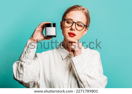 Portrait of beautiful blonde in white shirt with cream jat on blue background