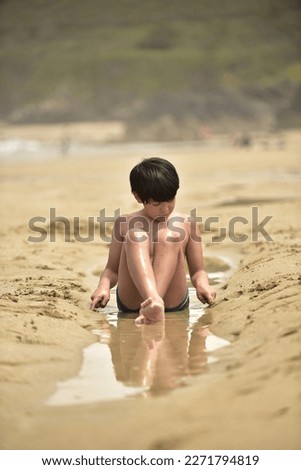 portrait of a seated child playing in the sand on the beach