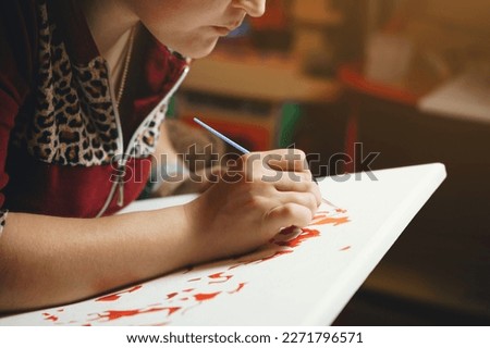 Girl paints a picture by numbers with paints.