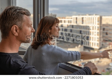 Man hugging his wife. Young couple moving in new apartmen. People looks out window at new houses. Concept new homes, new beginning. High quality photo