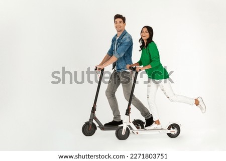 pretty stylish couple riding on electic kick scooter isolated on white studio background summer hipster style having fun together smiling happy, driving on speed Royalty-Free Stock Photo #2271803751