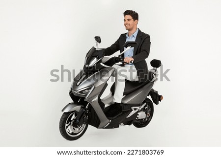 handsome man riding on electic motorbike scooter isolated on white studio background, standing attractive dressed in suit elegant young business hipster modern style, speed action