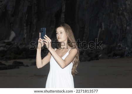 Woman hands holding mobile phone at sunset. Young woman taking photos with her cell phone in a beautiful amazing sunset over sea. Taking a picture on a smartphone during a vacation