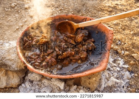Ancient food delicacies. Cooking rabbit stew in a clay cookware pot over a wood fire in rural Crete. Royalty-Free Stock Photo #2271815987