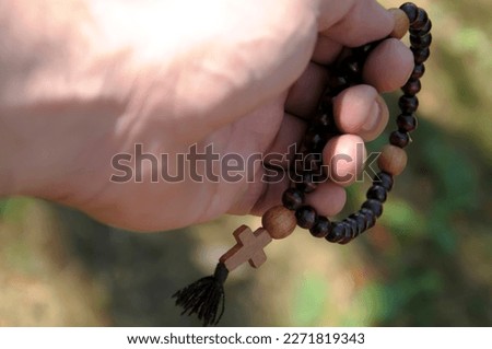 Close up view of male hand holding a rosary in nature. Concept for faith, spirituality and religion.