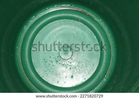 Bottom of empty green plastic bucket. 