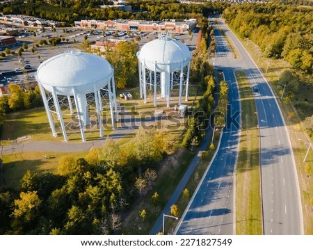 water tower near the road in a small town in the USA. Drone view. Autumn Forest, road, low-rise buildings.