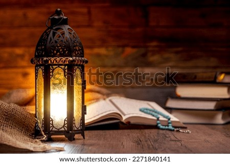 Islamic concept - The Holy Al Quran with written Arabic calligraphy meaning of Al Quran and a beautiful Arabian lamp, Arabic word translation : The Holy Al Quran (holy book of Muslim)
