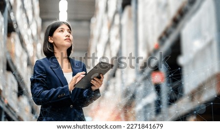 Business women use a digital tablet to manage the stock inventory on shelves in the large warehouse, smart cargo management system, supply chain and logistic network technology concept. Royalty-Free Stock Photo #2271841679