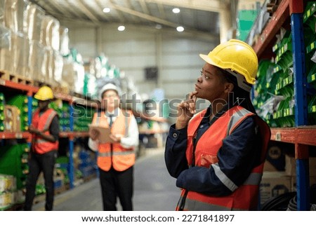Diversity of employee warehouse worker in safety vest and helmet working with tablet for checking products or parcel goods on shelf