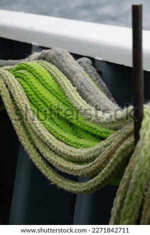close up of green and beige marine ropes strong boat ropes hanging together on side of ferry vertical format room for type boat travel background backdrop colorful rope lines used on ferry 