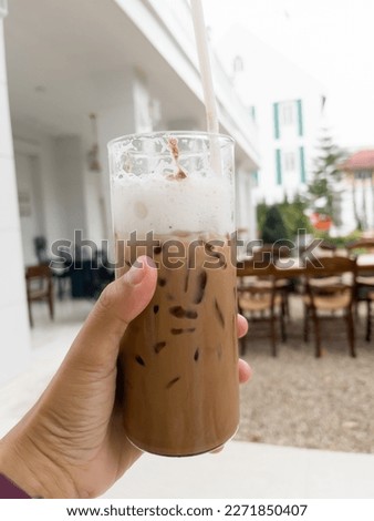 Hand holding glass of iced coffee mocha, stock photo