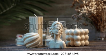 Beautiful white handmade candles of different shapes and sizes on a wooden background.