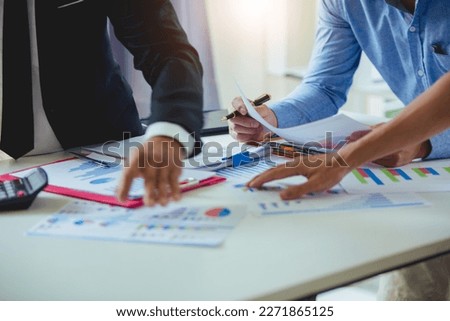 Businessmen analyzing investment graphs, brainstorming meeting and discussing plans in conference room. Using graph sheets, laptops and calculators. business and investment ideas