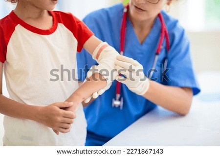 Child with arm injury at trauma and emergency care. Kid with elbow cast at health clinic. Doctor checking x-ray of injured little boy. Kids hospital.  Royalty-Free Stock Photo #2271867143