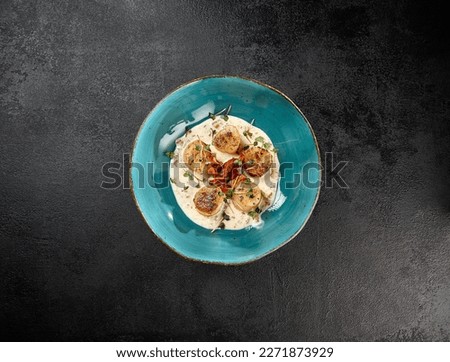 Fancy appetizer of grilled sea scallops in creamy sauce. Roasted sea scallops in cheese espuma in ceramic bowl on black concrete background. Seafood menu. Delicatessen sea scallop on dark stone table Royalty-Free Stock Photo #2271873929